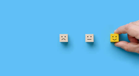 The customer hand picked the wooden block with happy face smile on blueの写真素材