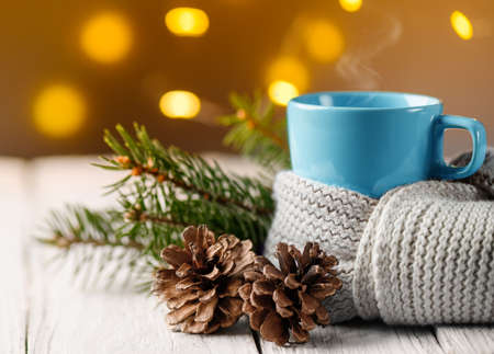 Cup of tea covered with warm scarf with pine cone and fir branch.の写真素材