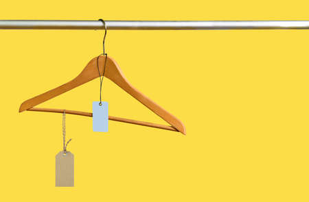 Empty coathanger with price tags in the store on yellow sale background. Major sell-off concept