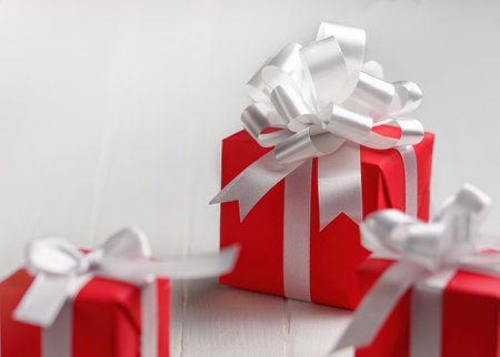 Red gift boxes with white bow on a white table background.の写真素材