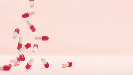 Falling red white capsules on a pink background.の写真素材