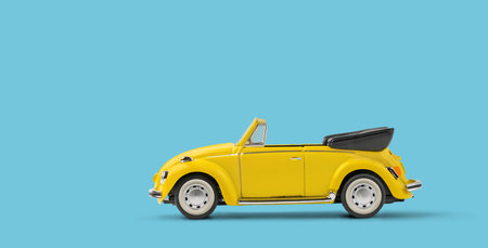 Miniature yellow toy convertible car on blue background with copyspaceの写真素材