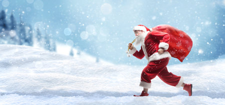 Santa Claus Running with a sack full of Christmas presents on snowy sceneryの写真素材