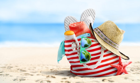 Summer beach bag and accessories on sandy beach and sea.の写真素材