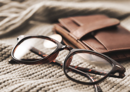 Stylish Eyeglasses and a Chic Wallet on Soft, Cozy Textiles for a Fashionable Lookの写真素材