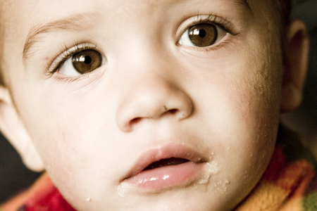 Curious male toddler with food on faceの写真素材