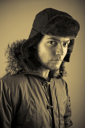 Male model dressed in parka and Ushanka hat. Vertical orientation, and sepia-toned.の写真素材