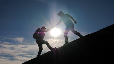 Teamwork Of Two Tourists Climbing To Top Of Mountain Giving Helping Hand