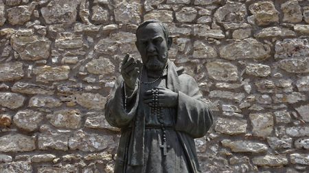 A statue of San Pio in front of a stone facade in Erice in Sicilyの写真素材