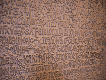 Antique characters in relief form on an old stone tabletの写真素材