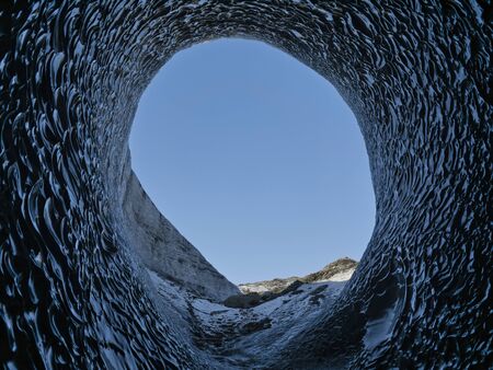 View through the large opening of a blue glacier cave in Iceland
