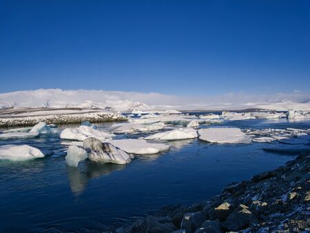 Several chunks of ice from the glacier in Iceland drift in calm water to the sea