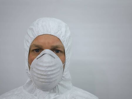 A man wearing a protective mask and a white hooded suit