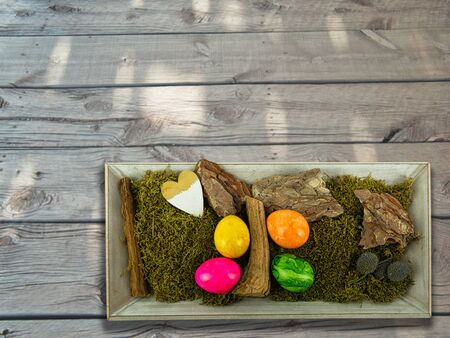Easter decoration in a wooden bowl on old wooden boards