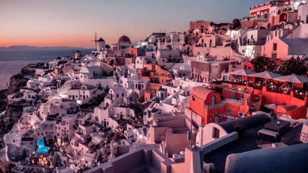 Sunset in Oia town, Santorini island, Greece. Traditional and famous white houses and churches with blue domes over the Caldera, Aegean seaの写真素材