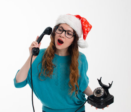Beautiful girl in Santas hat with old phone on white backgroundの写真素材