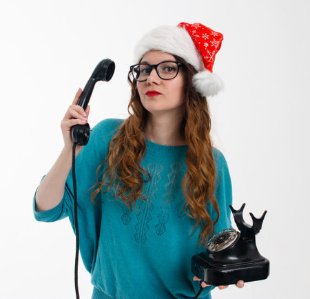 Beautiful girl in Santas hat with old phone on white backgroundの写真素材