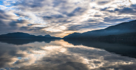 Mountain lake in the morning with reflection of mountains and cloudy sky