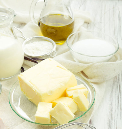 Ingredients for baking. Milk, sugar, butter and butter on a white wooden tableの写真素材