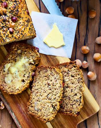 Whole grain bread with nuts, raisins and butter on wooden board