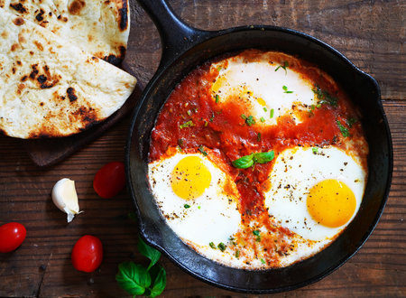 fried eggs with tomato sauce and naan bread, food closeupの写真素材