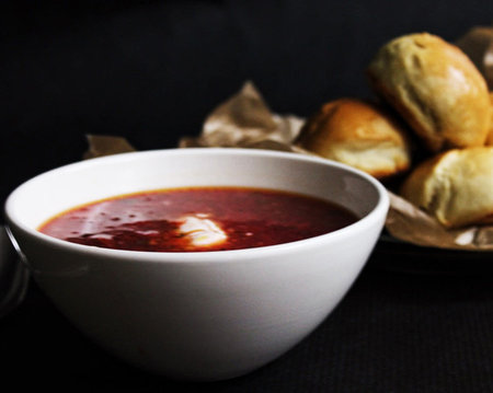 A bowl of red borscht on a black background with bunsの写真素材