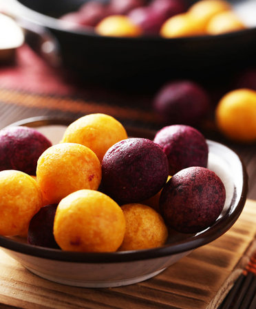 Deep-fried sweet potato balls in bowl on wooden table, closeupの写真素材