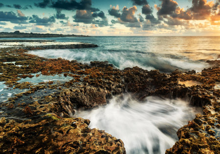Long exposure seascape with rocks and sea waves at sunset.の写真素材