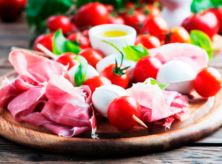 prosciutto with mozzarella and tomatoes on a wooden background. tinting. selective focusの写真素材