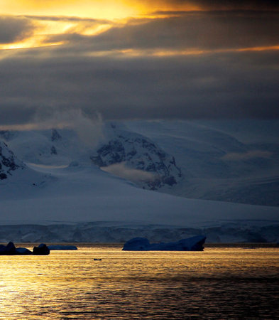 Antarctic landscape with icebergs in the ocean and mountains in the backgroundの写真素材