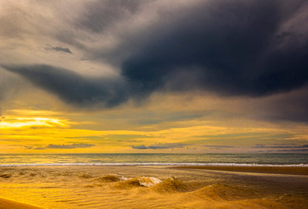 Tropical beach with stormy sky and golden sand at sunsetの写真素材