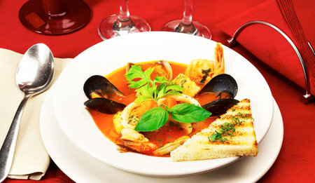 Seafood soup with mussels in tomato sauce on a white plateの写真素材