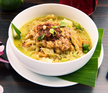 green curry with coconut milk and chicken in white bowl on wooden tableの写真素材