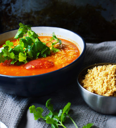 Tomato soup with coriander in a ceramic bowl on the tableの写真素材