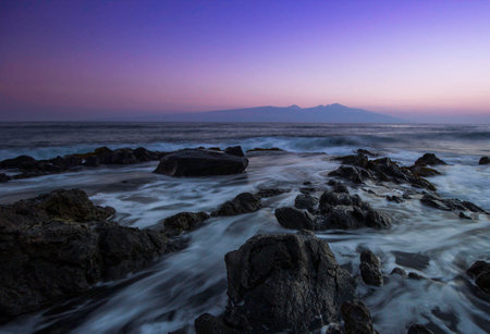 Long exposure of the sea and mountain in the background at sunset.の写真素材