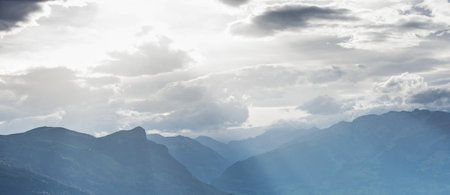 Panoramic view of the mountains with clouds and sun rays.