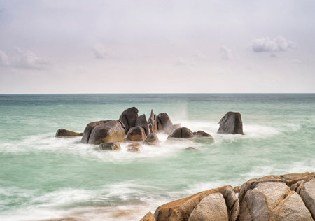 tropical beach under the blue sky with white clouds and stony bottomの写真素材