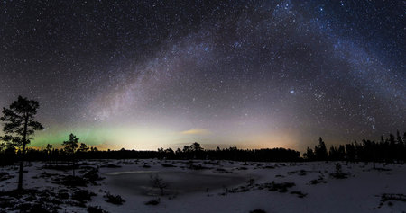 Milky Way over the lake and pine forest in the winter.の写真素材