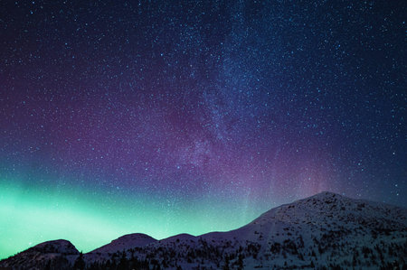 Aurora borealis in the night sky over the snowy mountainsの写真素材