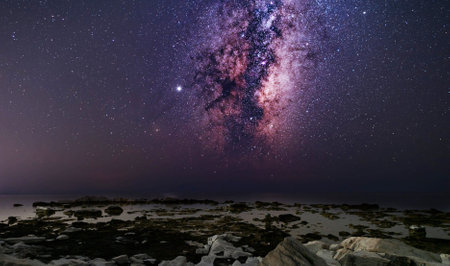 Milky Way over the sea with rocks and stones in the foregroundの写真素材