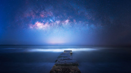 Milky way over jetty at night. Long exposure photograph.の写真素材