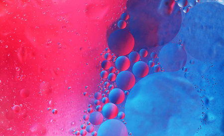 bright oily drops in water with colorful background, close-up shot