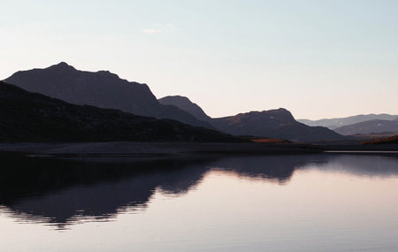 Reflection of mountains in the water of a lake at sunset.