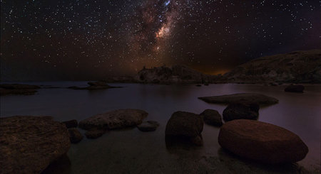 Milky Way over the sea with rocks and starry sky.