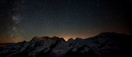 Night starry sky with milky way over snowy mountains. Panoramaの写真素材