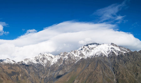 Mountain landscape with snow-capped peaks in the clouds.
