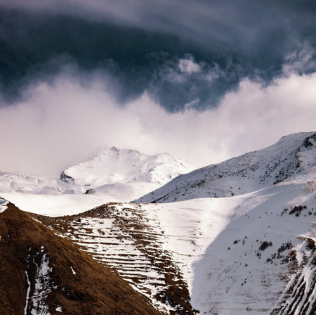 Snowy mountains under cloudy sky. Caucasus Mountains, Georgia, region Gudauri.