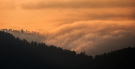 Foggy sunrise in the mountains. Beautiful sky with clouds.