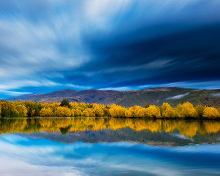 Colorful autumn landscape with lake and mountains reflected in water at sunset