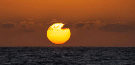 Sunset in the sea. The sun sets behind the clouds.の写真素材